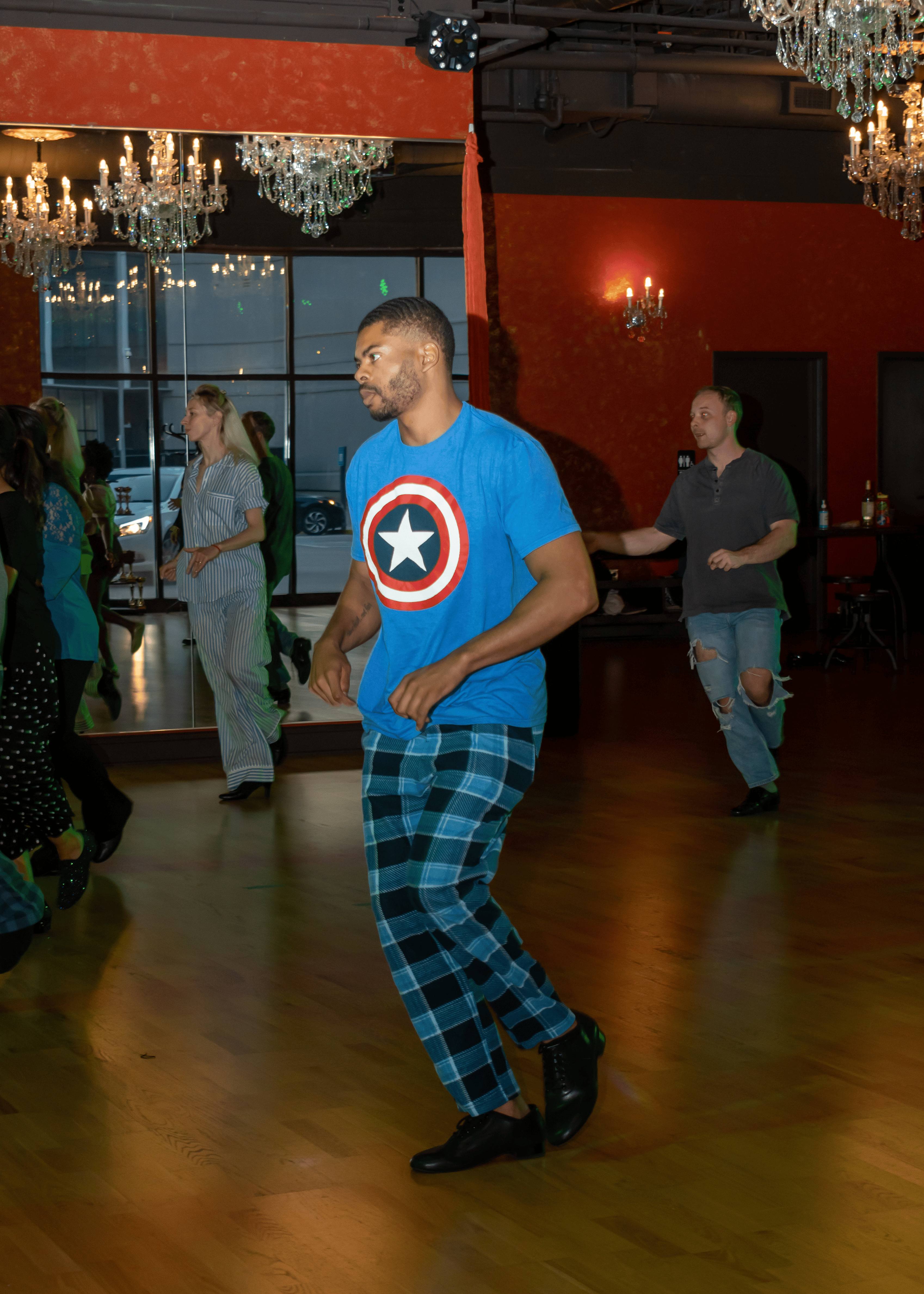 Miles dancing on a ballroom social dance floor under chandeliers